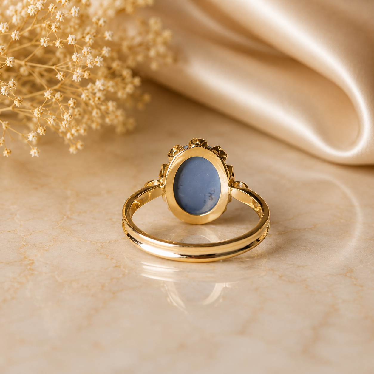 Gold ring with a blue stone on a beige fabric background