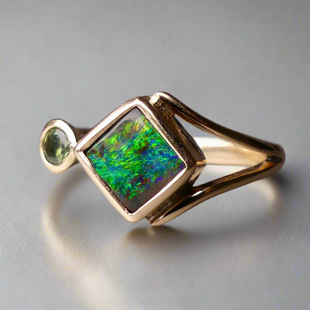 Discover the elegance of this unique 9k gold Australian Boulder Opal ring, beautifully paired with a stunning Australian sapphire. The vibrant opal’s natural patterns and the sapphire’s green blue hues create a captivating contrast, making this ring a true statement piece.