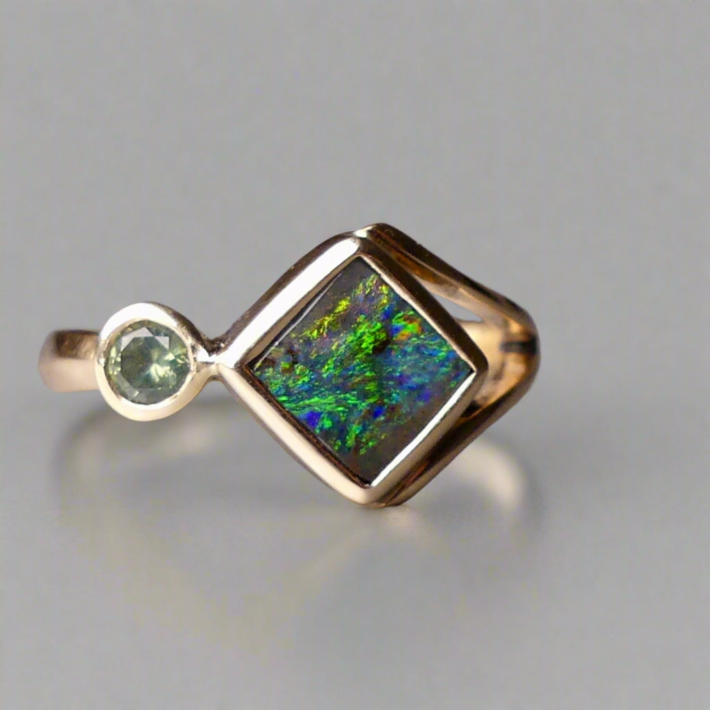Discover the elegance of this unique 9k gold Australian Boulder Opal ring, beautifully paired with a stunning Australian sapphire. The vibrant opal’s natural patterns and the sapphire’s green blue hues create a captivating contrast, making this ring a true statement piece.