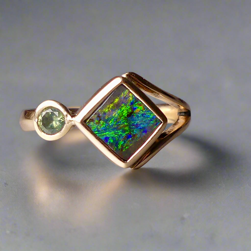 Discover the elegance of this unique 9k gold Australian Boulder Opal ring, beautifully paired with a stunning Australian sapphire. The vibrant opal’s natural patterns and the sapphire’s green blue hues create a captivating contrast, making this ring a true statement piece.