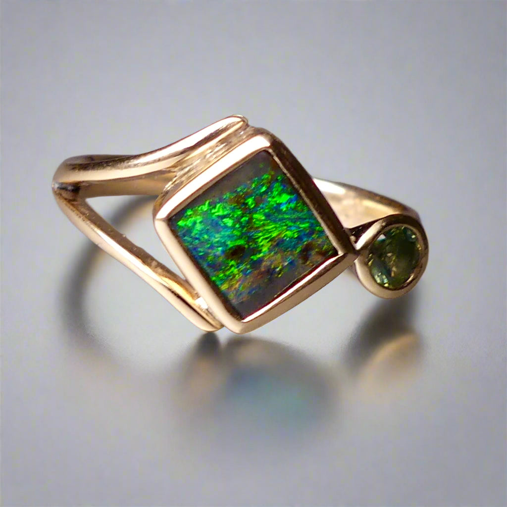 Discover the elegance of this unique 9k gold Australian Boulder Opal ring, beautifully paired with a stunning Australian sapphire. The vibrant opal’s natural patterns and the sapphire’s green blue hues create a captivating contrast, making this ring a true statement piece.