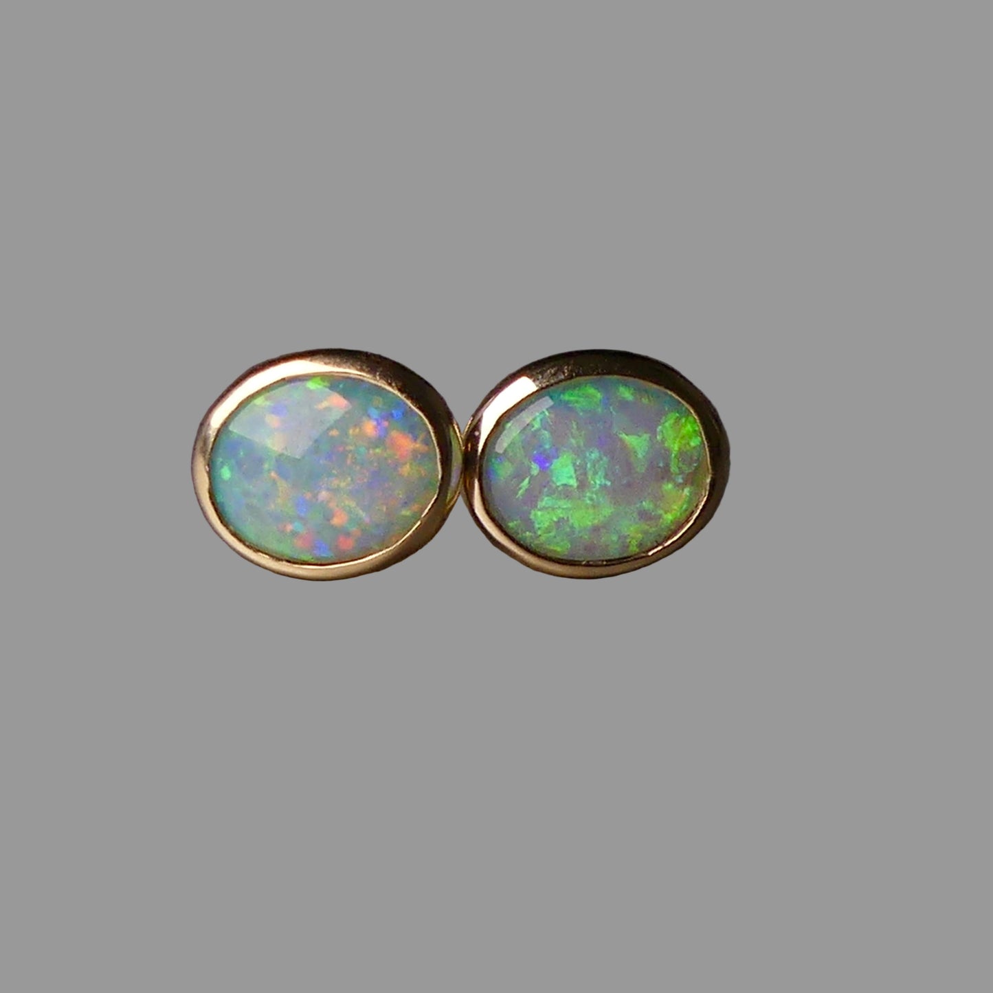 Pair of opal stud earrings with gold setting on a dark background