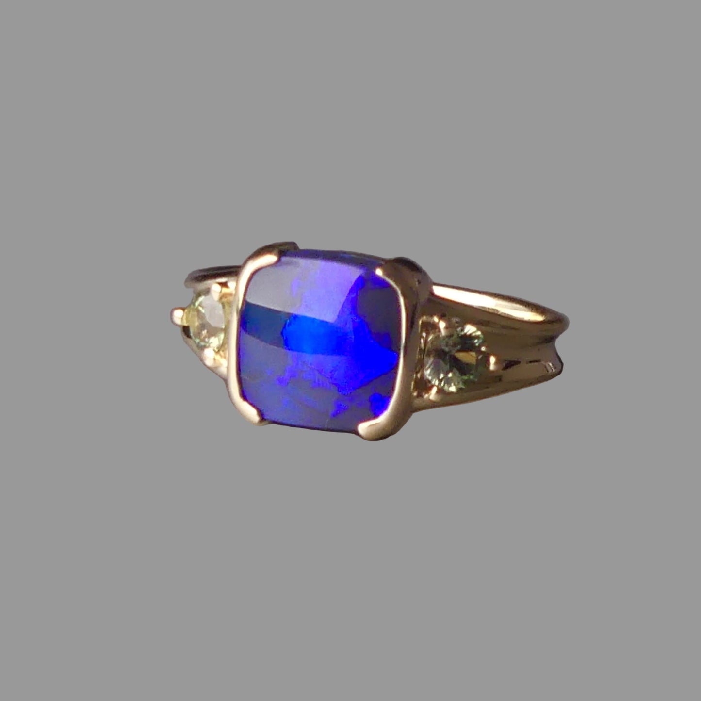 Gold ring with a blue gemstone on a gray background