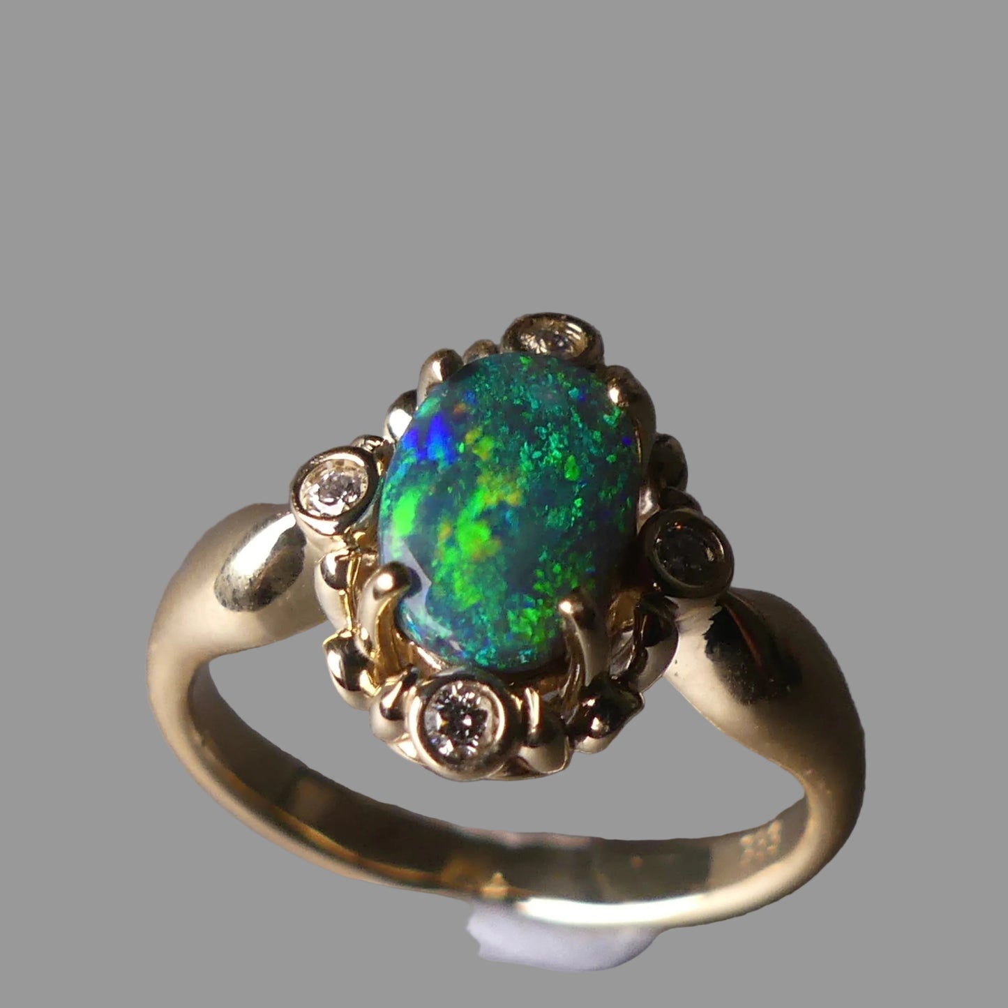 Gold ring with a green opal stone on a gray background