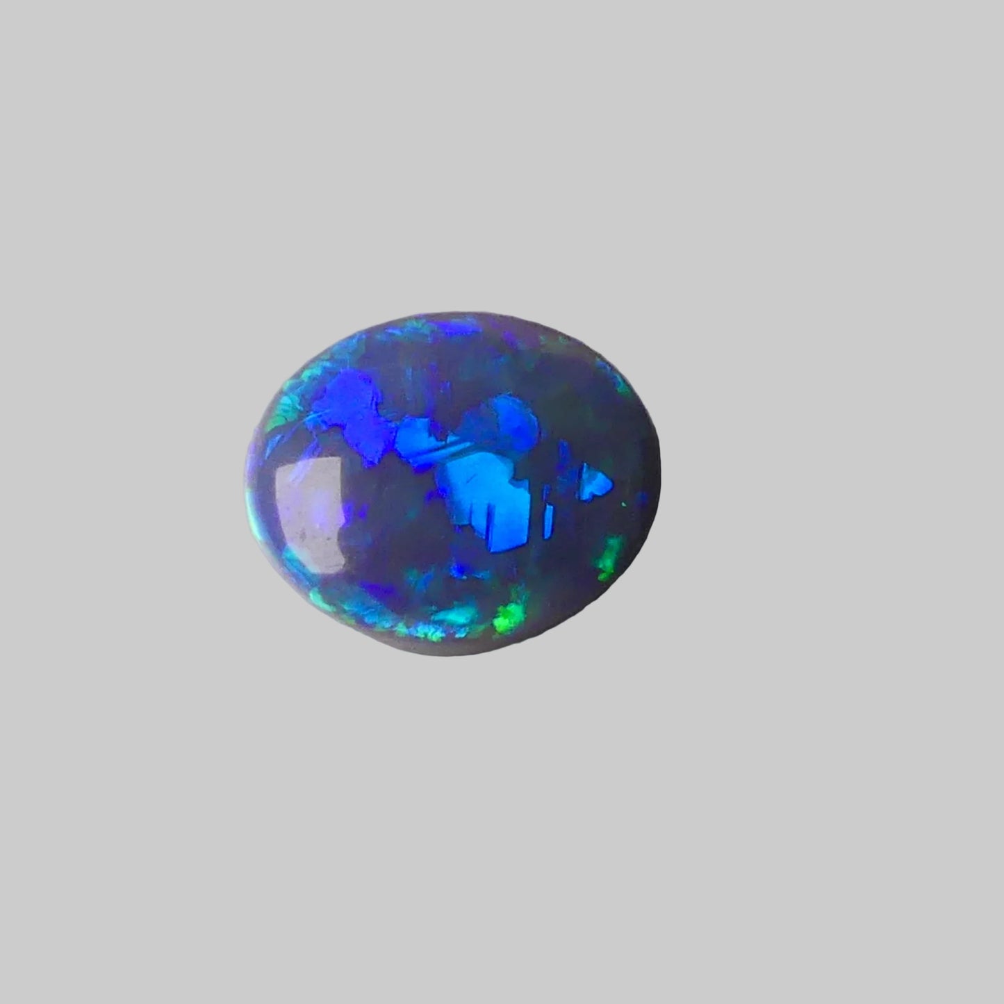 Opal stone with blue and green fluorescence on a gray background
