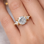 Gold ring with a large diamond and smaller diamonds on a finger