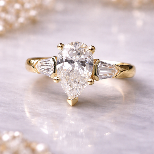 Gold ring with a pear-shaped diamond on a light background