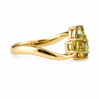 A yellow gold ring featuring a cluster of three light green gemstones in a prong setting, shown on a clean white background.