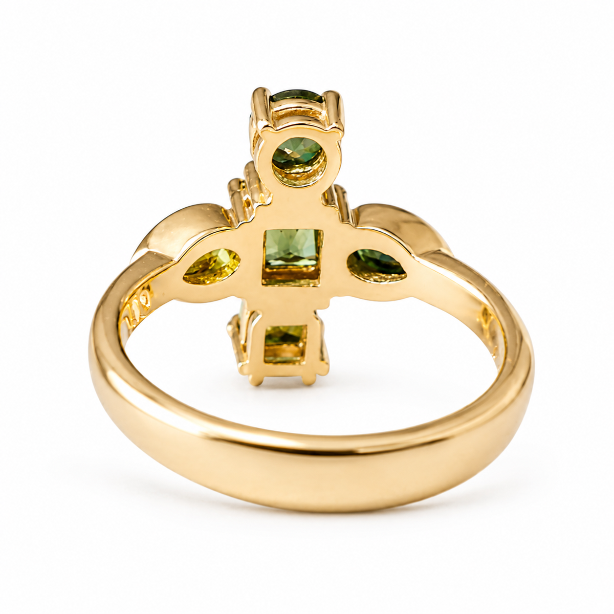 A gold ring with a decorative top featuring green gemstones, shown on a plain white background.