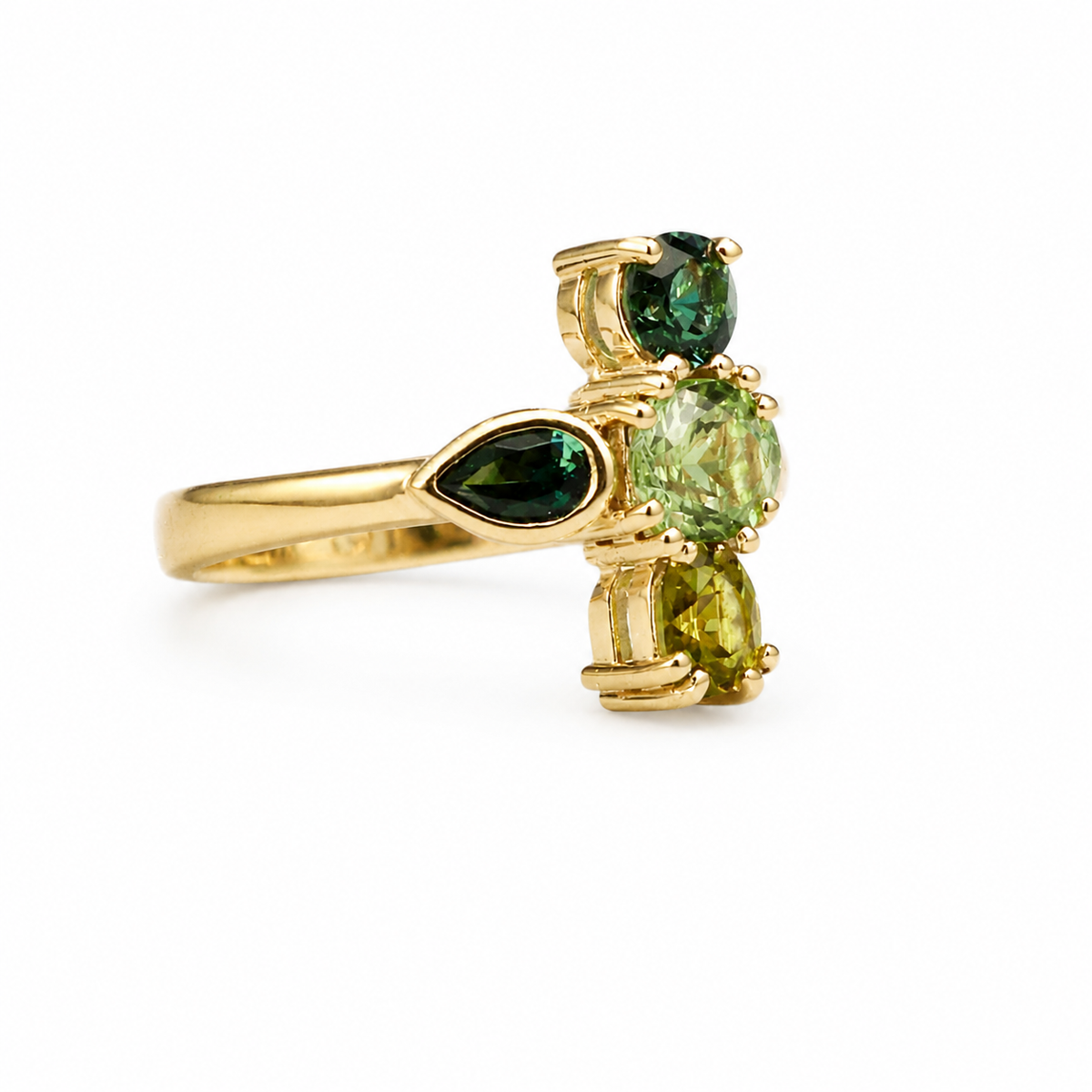 A yellow gold ring featuring three green gemstones in a cluster setting, photographed on a clean white background.
