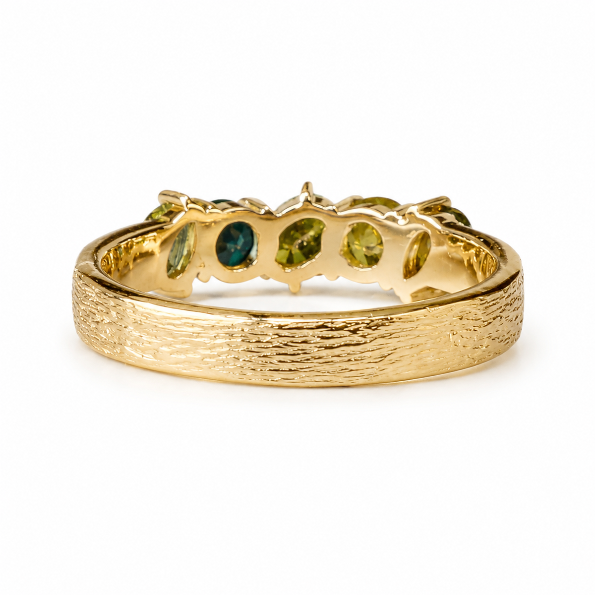 A textured yellow gold ring featuring a row of green gemstone accents, photographed on a clean white background.