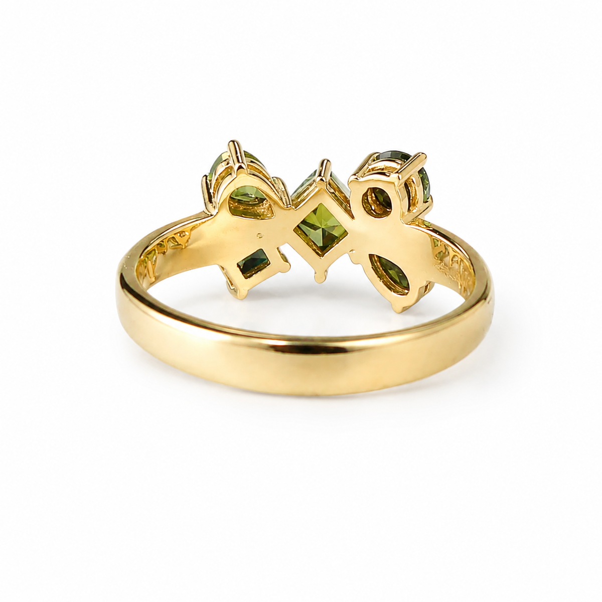A yellow gold ring featuring a decorative top with green gemstone accents, shown on a plain white background.