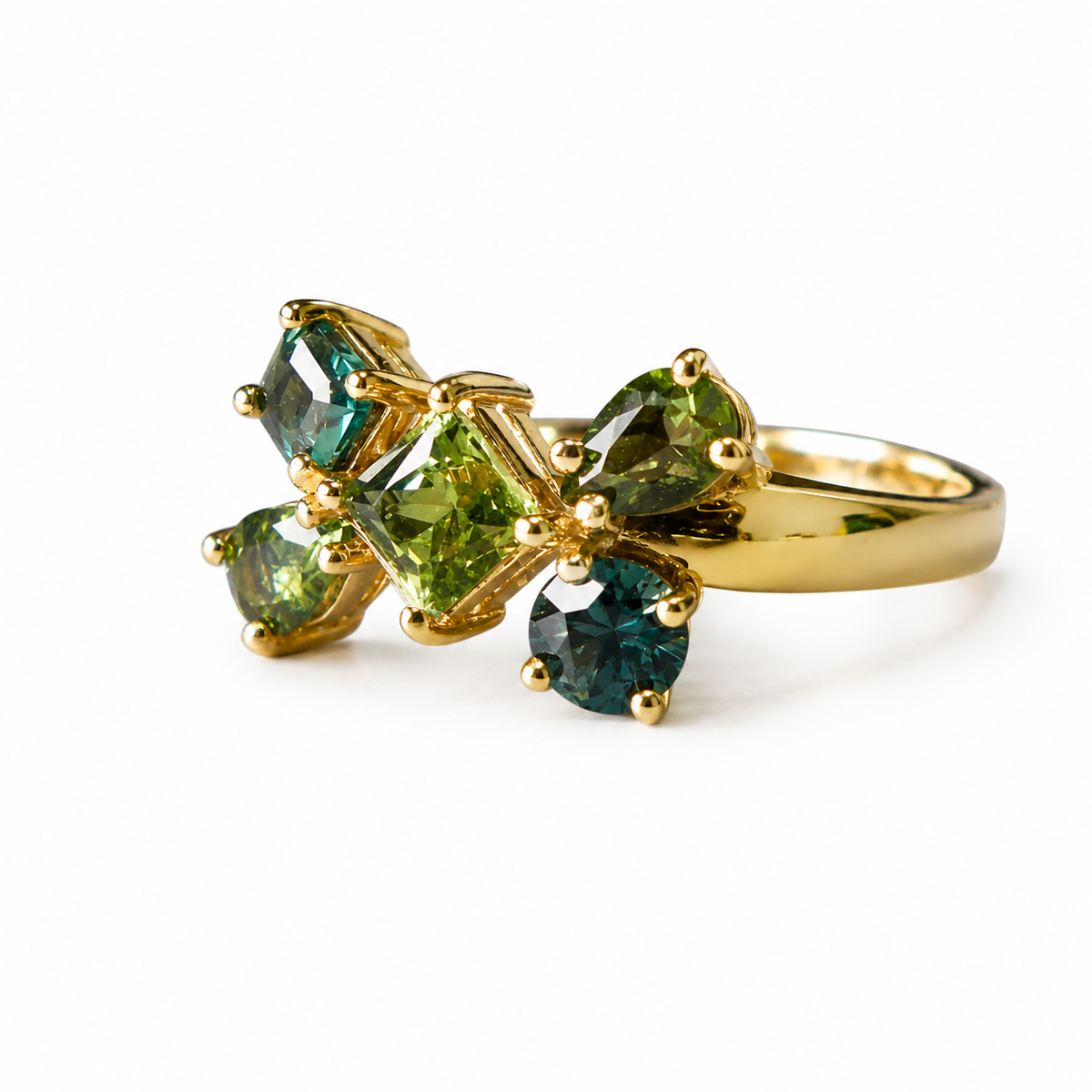 A gold ring featuring a cluster of green gemstones in marquise and rectangular shapes, photographed on a clean white background.