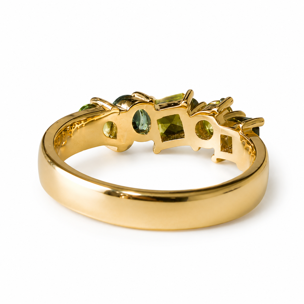 A gold ring featuring a wide polished band and a decorative top set with olive green gemstones in a geometric, openwork design, shown on a white background.