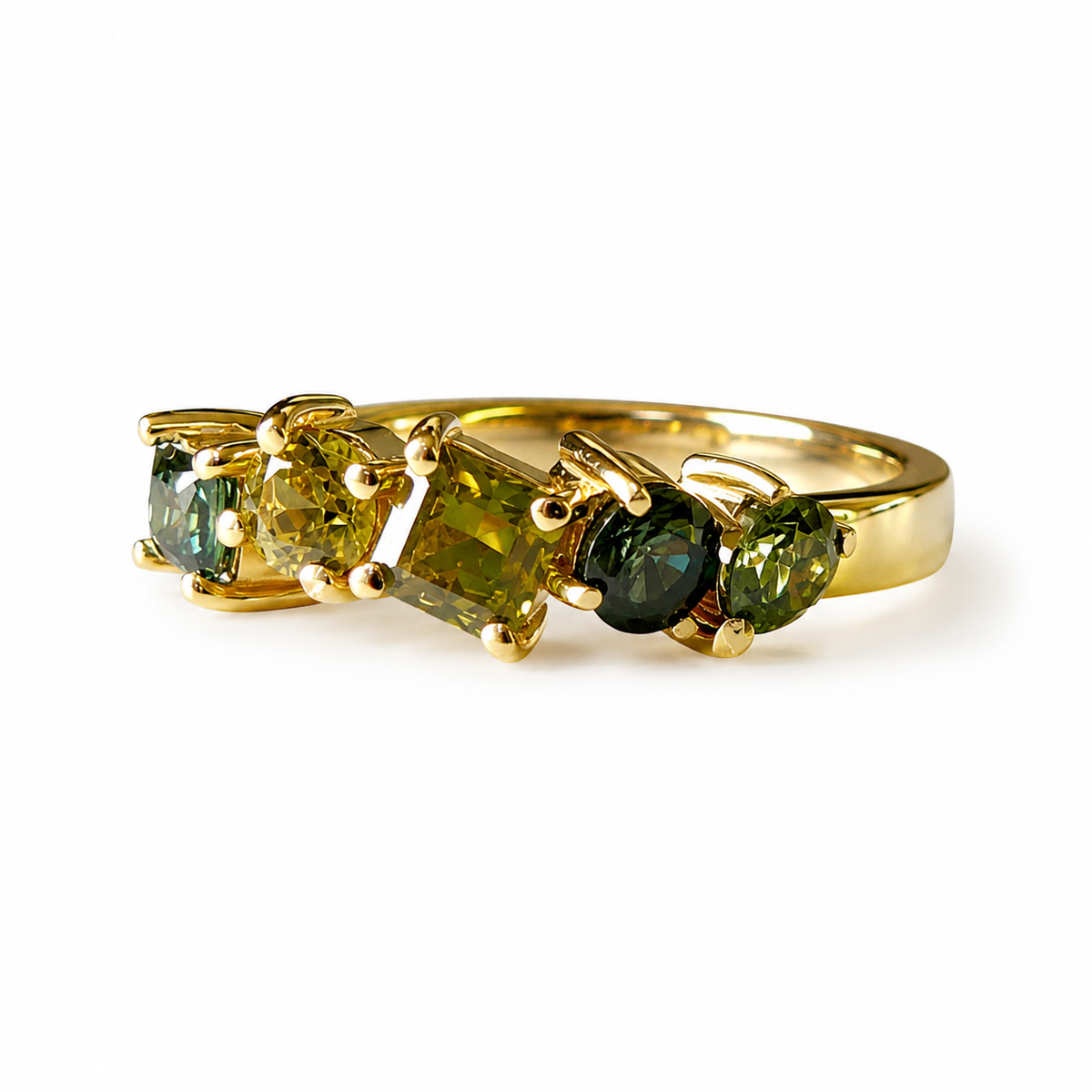 A yellow gold ring featuring three marquise-cut green gemstones in a row, set against a clean white background.