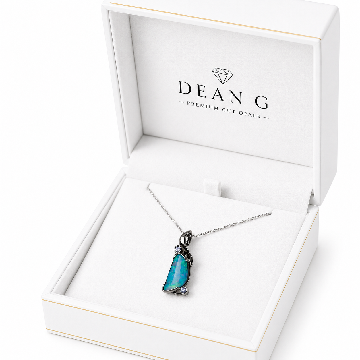 A DEANG brand necklace with a vibrant blue-green opal pendant in a silver setting, presented inside an open white jewelry box.