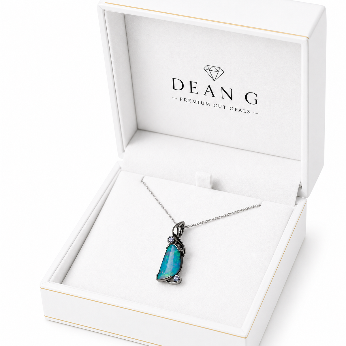 A DEANG brand necklace with a vibrant blue-green opal pendant in a silver setting, presented inside an open white jewelry box.