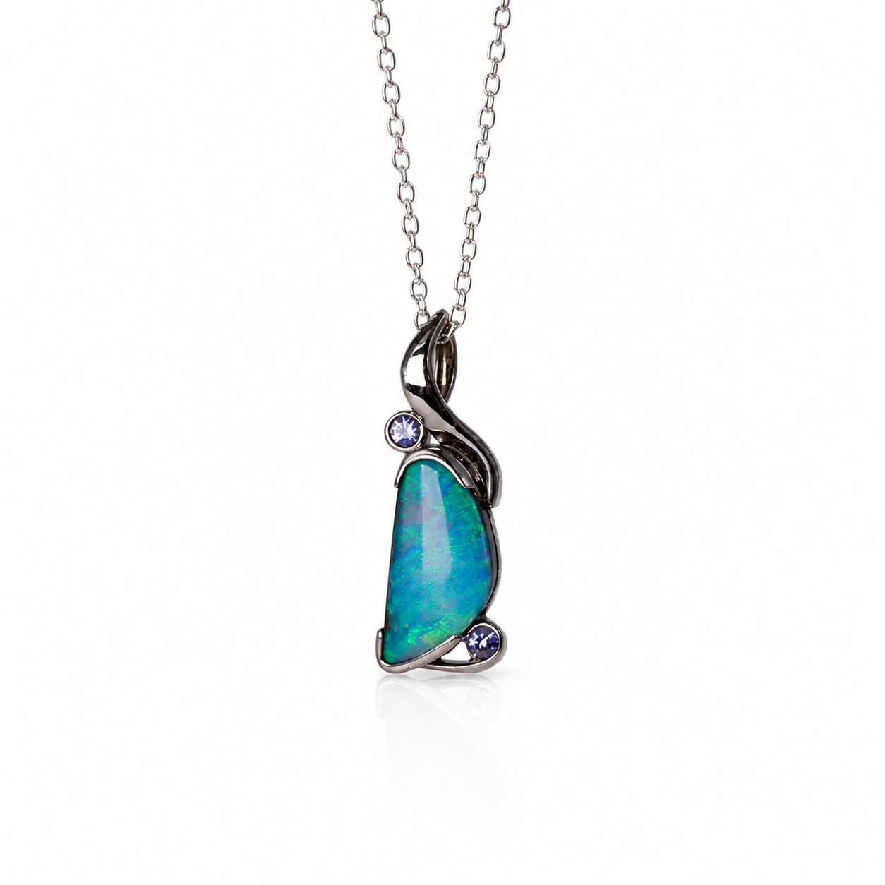 A silver pendant necklace featuring a teardrop-shaped iridescent opal stone with blue and green flashes, accented by two small round purple gemstones, shown on a white background.