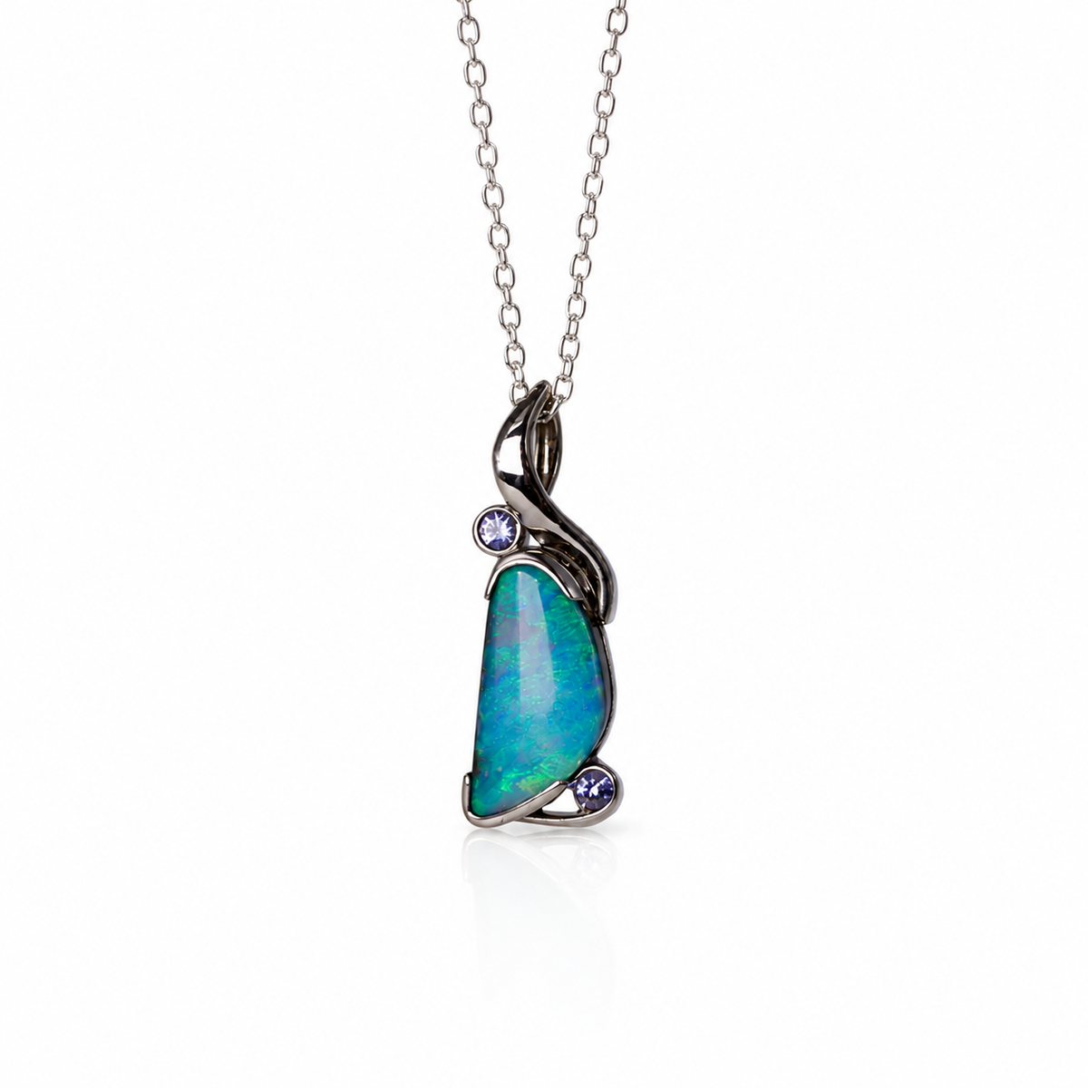 A silver pendant necklace featuring a teardrop-shaped iridescent opal stone with blue and green flashes, accented by two small round purple gemstones, shown on a white background.