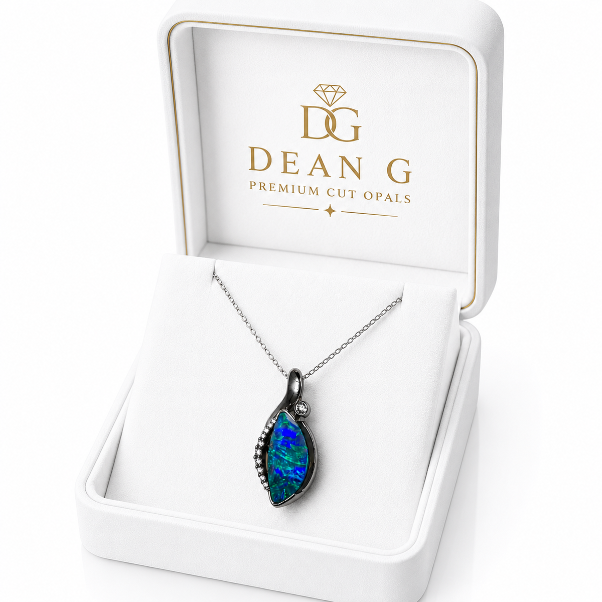 A teardrop-shaped cut opal pendant necklace with a dark metal setting, displayed inside an open white Dean G Premium Cut Opals gift box.