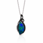 A silver pendant necklace featuring a teardrop-shaped opal stone with vibrant blue and green play-of-color, accented by small clear pavé stones along the left edge and a single round clear stone near the top, suspended from a delicate silver chain on a white background.