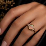 Ring with an opal stone on a hand against a dark background