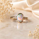Gold ring with a colorful gemstone on a soft beige fabric background