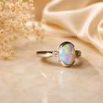 Opal ring with gold setting on a beige fabric background