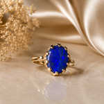 Gold ring with a blue gemstone on a beige fabric background