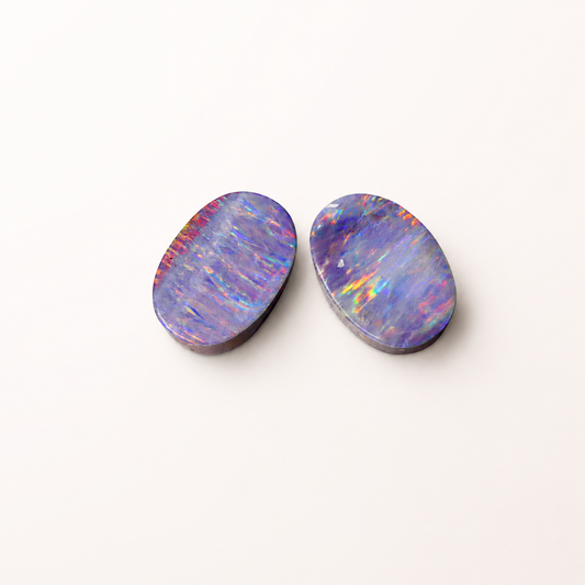 Two colorful opal stones on a white background