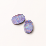 Two oval-shaped opal stones on a white background