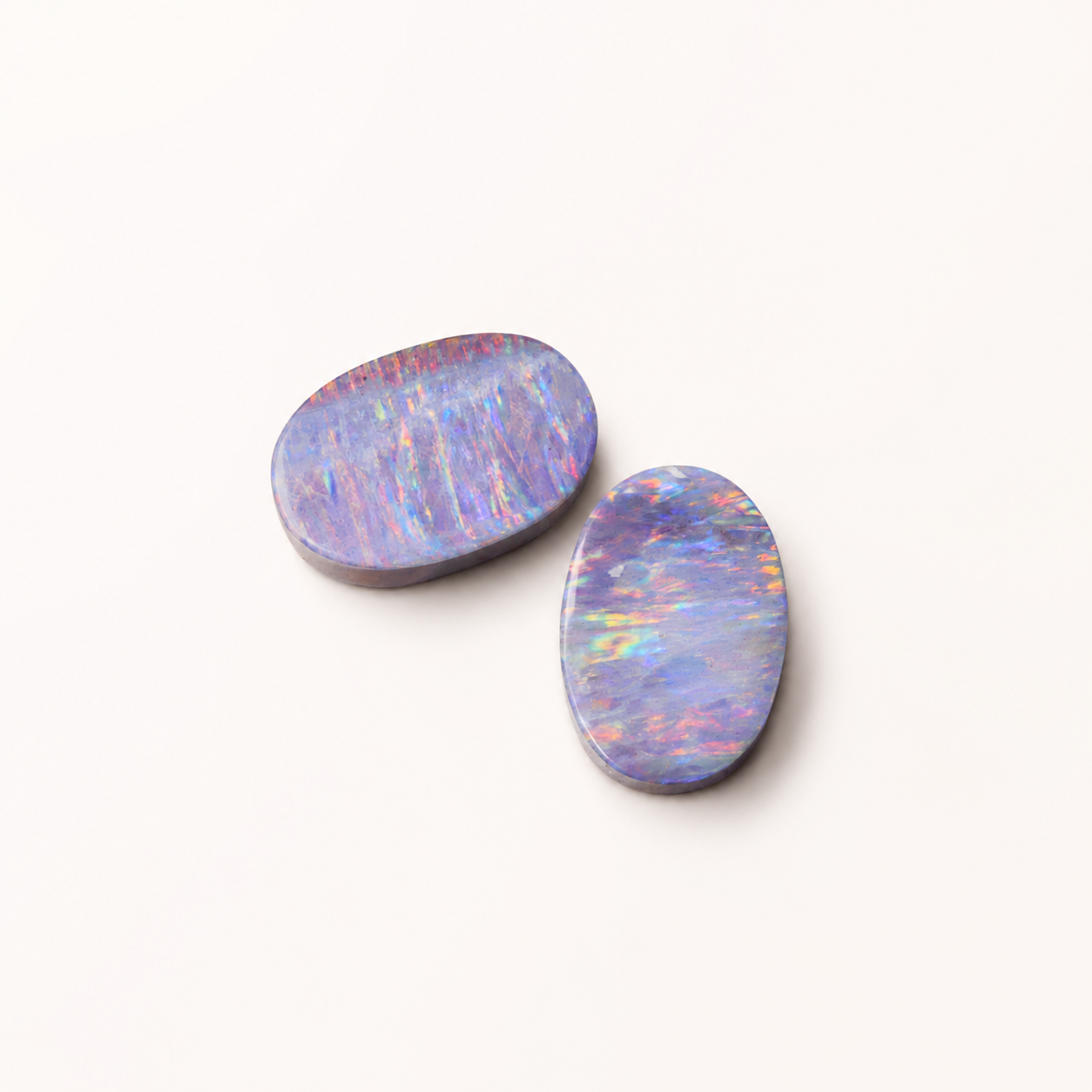 Two oval-shaped opal stones on a white background