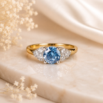 Gold ring with a blue gemstone on a beige fabric background