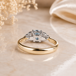 Gold ring with diamonds and a blue gemstone on a beige background