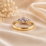 Gold and silver ring with a pink gemstone on beige fabric