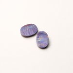 Two oval-shaped opal stones on a white background