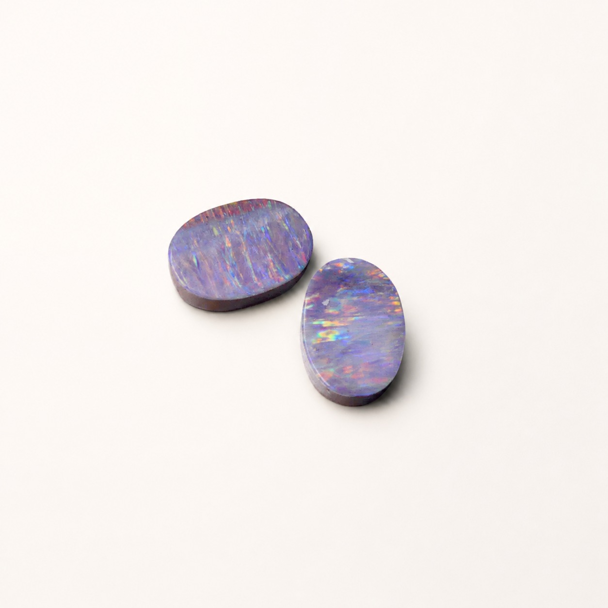 Two oval-shaped opal stones on a white background