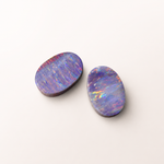 Two colorful opal stones on a white background