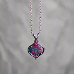 This stunning 18k white gold pendant features a rare and captivating Australian black opal accented with a brilliant center diamond and stunning rubies. Elevate your look with this breathtaking piece and indulge in the unique beauty and elegance of this precious gemstone.

Opal Weight- 1.6ct Australian Black Opal

Opal Origin- Lightning Ridge Australia

Setting- Rhodium Plated 18k White Gold

Accent Stones- Center Diamond, Rubies

Chain- 18k White Gold 45cm in length
