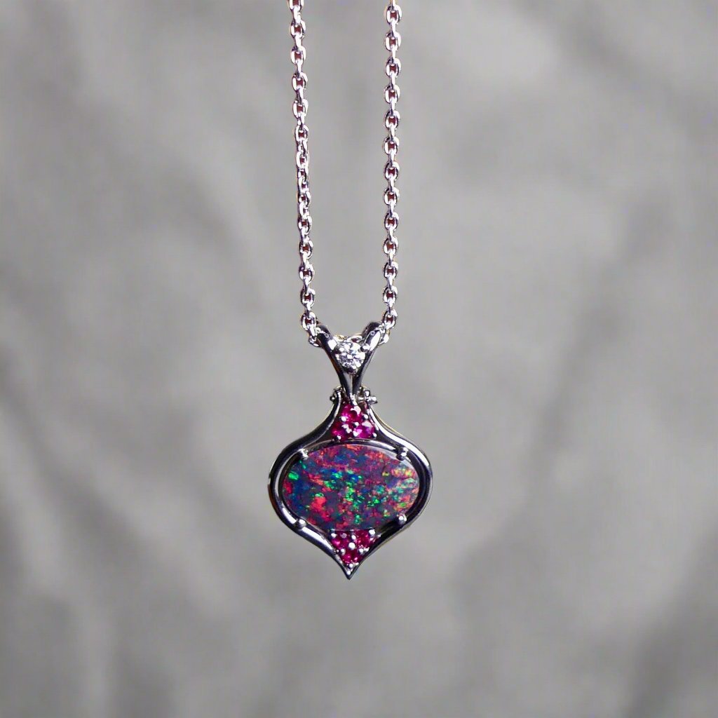 This stunning 18k white gold pendant features a rare and captivating Australian black opal accented with a brilliant center diamond and stunning rubies. Elevate your look with this breathtaking piece and indulge in the unique beauty and elegance of this precious gemstone.

Opal Weight- 1.6ct Australian Black Opal

Opal Origin- Lightning Ridge Australia

Setting- Rhodium Plated 18k White Gold

Accent Stones- Center Diamond, Rubies

Chain- 18k White Gold 45cm in length
