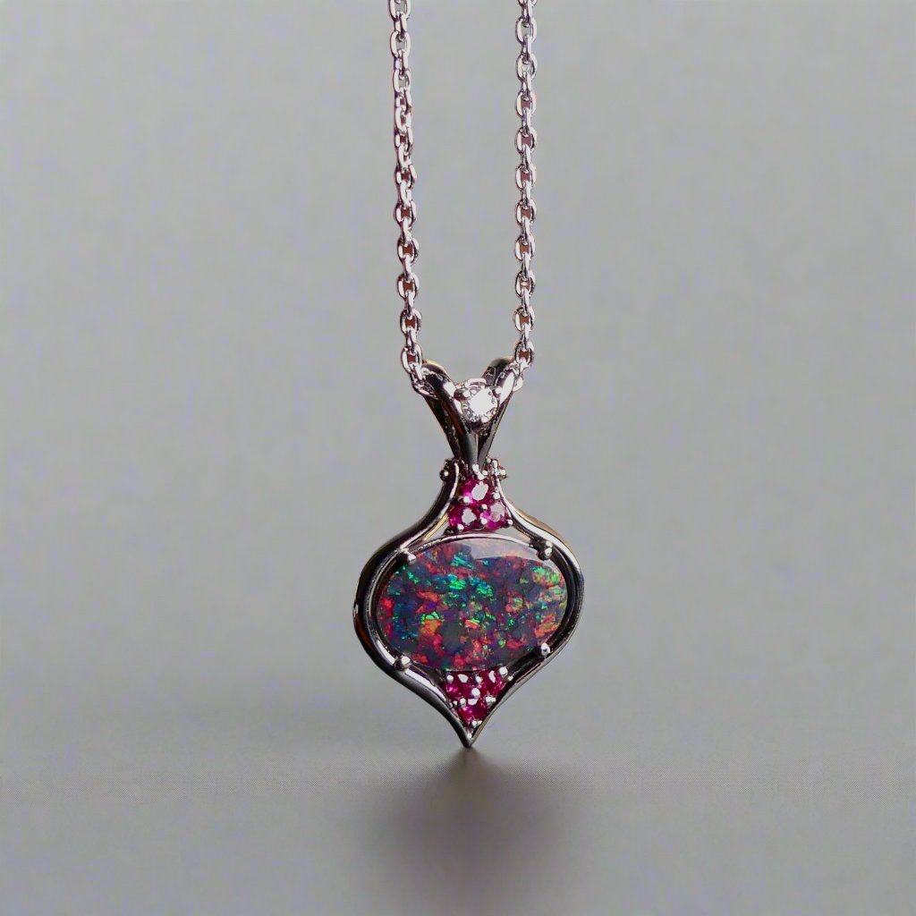This stunning 18k white gold pendant features a rare and captivating Australian black opal accented with a brilliant center diamond and stunning rubies. Elevate your look with this breathtaking piece and indulge in the unique beauty and elegance of this precious gemstone.

Opal Weight- 1.6ct Australian Black Opal

Opal Origin- Lightning Ridge Australia

Setting- Rhodium Plated 18k White Gold

Accent Stones- Center Diamond, Rubies

Chain- 18k White Gold 45cm in length
