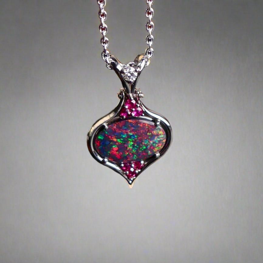 This stunning 18k white gold pendant features a rare and captivating Australian black opal accented with a brilliant center diamond and stunning rubies. Elevate your look with this breathtaking piece and indulge in the unique beauty and elegance of this precious gemstone.

Opal Weight- 1.6ct Australian Black Opal

Opal Origin- Lightning Ridge Australia

Setting- Rhodium Plated 18k White Gold

Accent Stones- Center Diamond, Rubies

Chain- 18k White Gold 45cm in length
