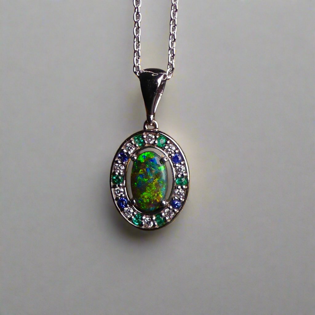 Lightning Ridge Australian black opal with strong, highly prized colors of reds, orange, and yellows is undoubtedly a remarkable gemstone. Expertly crafted from 18k white gold, this pendant showcases the mesmerizing beauty of an Australian black opal, surrounded by sparkling diamonds, emeralds, and sapphires. Exquisite in design and quality, this pendant is a luxurious addition to any jewelry collection. Elevate your style with this stunning piece.

Opal Weight- 1.1ct

Body Tone- N1 Australian Black