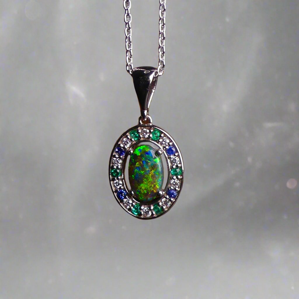 Lightning Ridge Australian black opal with strong, highly prized colors of reds, orange, and yellows is undoubtedly a remarkable gemstone. Expertly crafted from 18k white gold, this pendant showcases the mesmerizing beauty of an Australian black opal, surrounded by sparkling diamonds, emeralds, and sapphires. Exquisite in design and quality, this pendant is a luxurious addition to any jewelry collection. Elevate your style with this stunning piece.

Opal Weight- 1.1ct

Body Tone- N1 Australian Black
