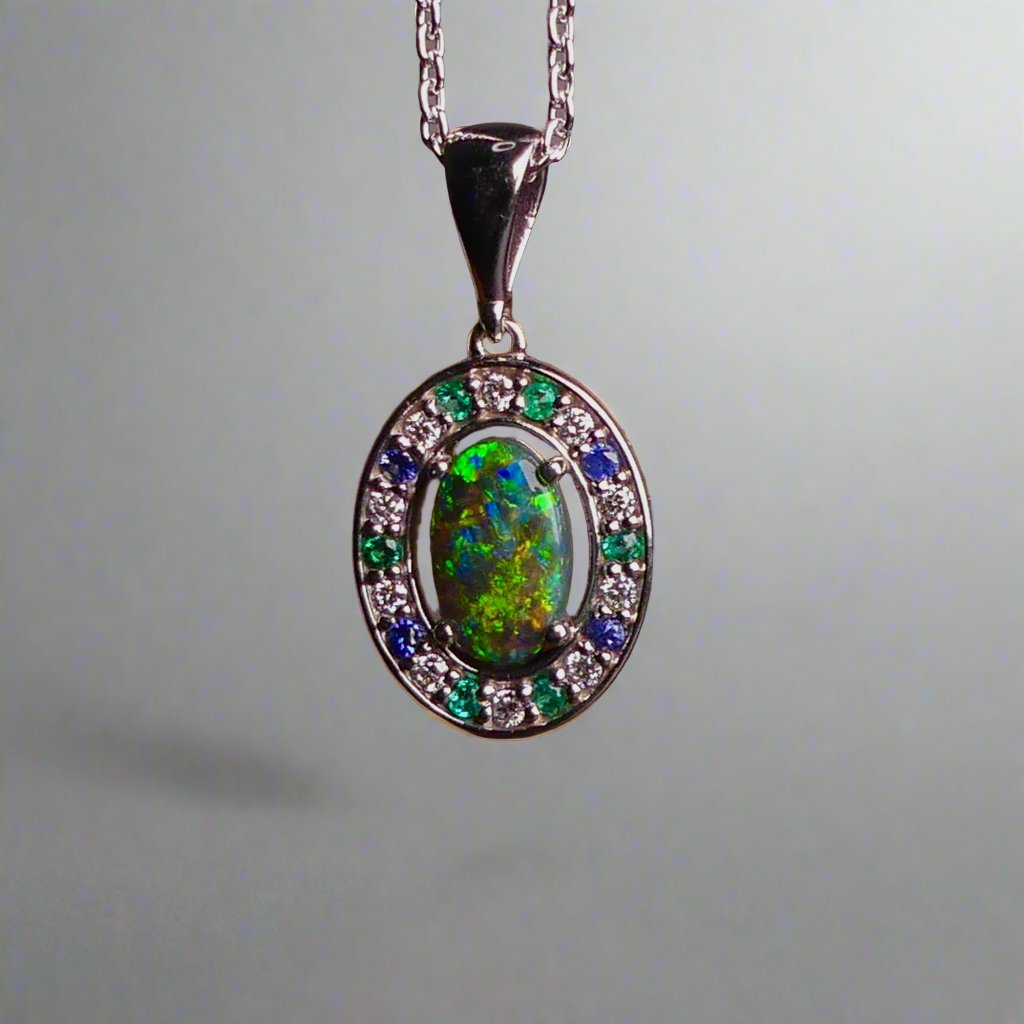 Lightning Ridge Australian black opal with strong, highly prized colors of reds, orange, and yellows is undoubtedly a remarkable gemstone. Expertly crafted from 18k white gold, this pendant showcases the mesmerizing beauty of an Australian black opal, surrounded by sparkling diamonds, emeralds, and sapphires. Exquisite in design and quality, this pendant is a luxurious addition to any jewelry collection. Elevate your style with this stunning piece.

Opal Weight- 1.1ct

Body Tone- N1 Australian Black