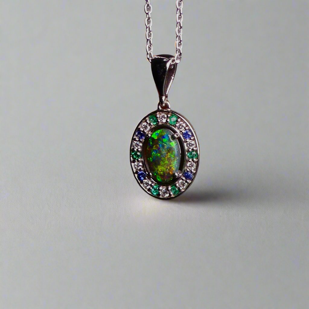 Lightning Ridge Australian black opal with strong, highly prized colors of reds, orange, and yellows is undoubtedly a remarkable gemstone. Expertly crafted from 18k white gold, this pendant showcases the mesmerizing beauty of an Australian black opal, surrounded by sparkling diamonds, emeralds, and sapphires. Exquisite in design and quality, this pendant is a luxurious addition to any jewelry collection. Elevate your style with this stunning piece.

Opal Weight- 1.1ct

Body Tone- N1 Australian Black