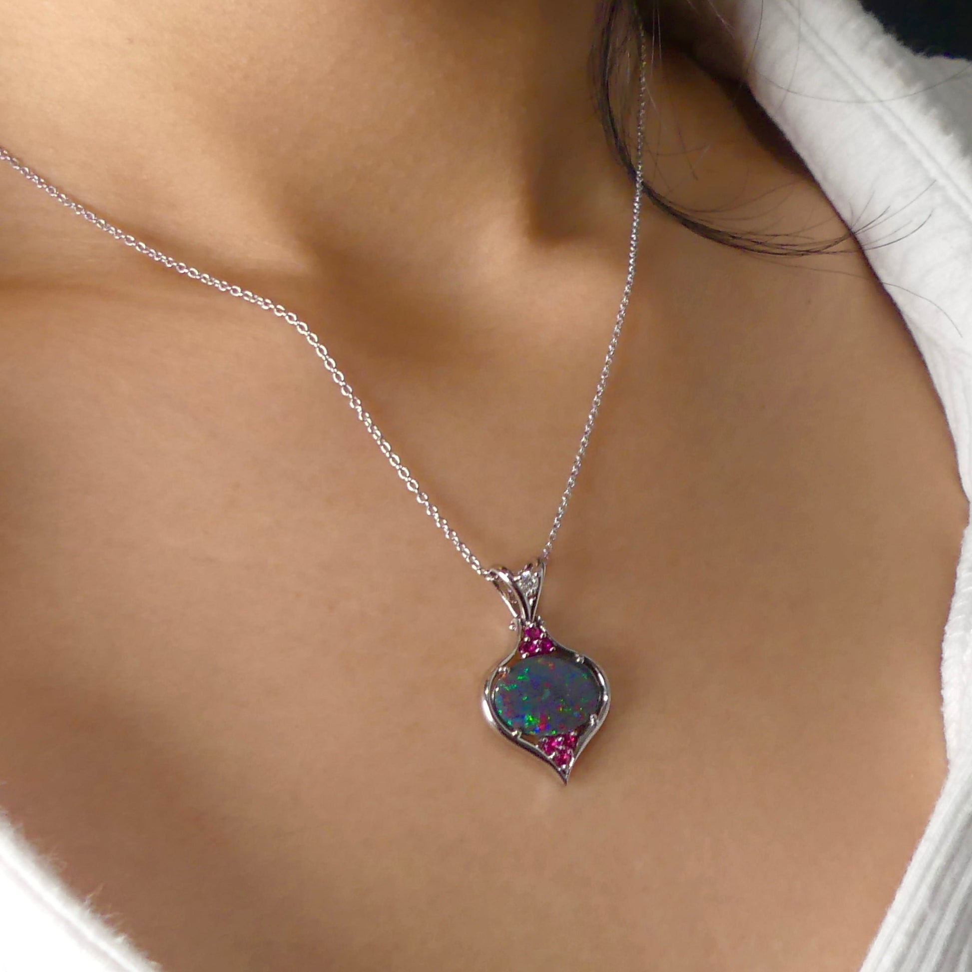 This stunning 18k white gold pendant features a rare and captivating Australian black opal accented with a brilliant center diamond and stunning rubies. Elevate your look with this breathtaking piece and indulge in the unique beauty and elegance of this precious gemstone.

Opal Weight- 1.6ct Australian Black Opal

Opal Origin- Lightning Ridge Australia

Setting- Rhodium Plated 18k White Gold

Accent Stones- Center Diamond, Rubies

Chain- 18k White Gold 45cm in length
