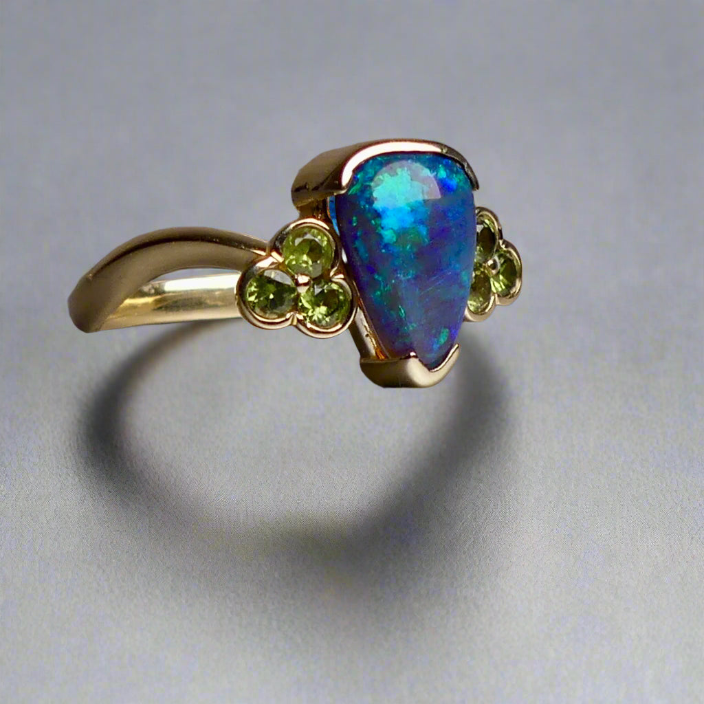 Indulge in timeless elegance with our 14k Australian Black Opal Ring. Crafted with a stunning black opal, this ring showcases mesmerizing blue and green colors. Each piece is unique, making it the perfect addition to any jewelry collection. Elevate your style with this timeless and luxurious ring.

Opal- 1.6ct Australian Black Opal

Origin-Lightning Ridge Australia

Setting- 14k Yellow Gold Bezel Set

Accent Stones- Forrest Green Sapphires

Size- 7 1/4 us
