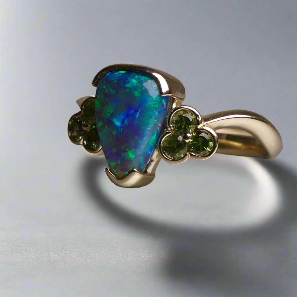 Indulge in timeless elegance with our 14k Australian Black Opal Ring. Crafted with a stunning black opal, this ring showcases mesmerizing blue and green colors. Each piece is unique, making it the perfect addition to any jewelry collection. Elevate your style with this timeless and luxurious ring.

Opal- 1.6ct Australian Black Opal

Origin-Lightning Ridge Australia

Setting- 14k Yellow Gold Bezel Set

Accent Stones- Forrest Green Sapphires

Size- 7 1/4 us
