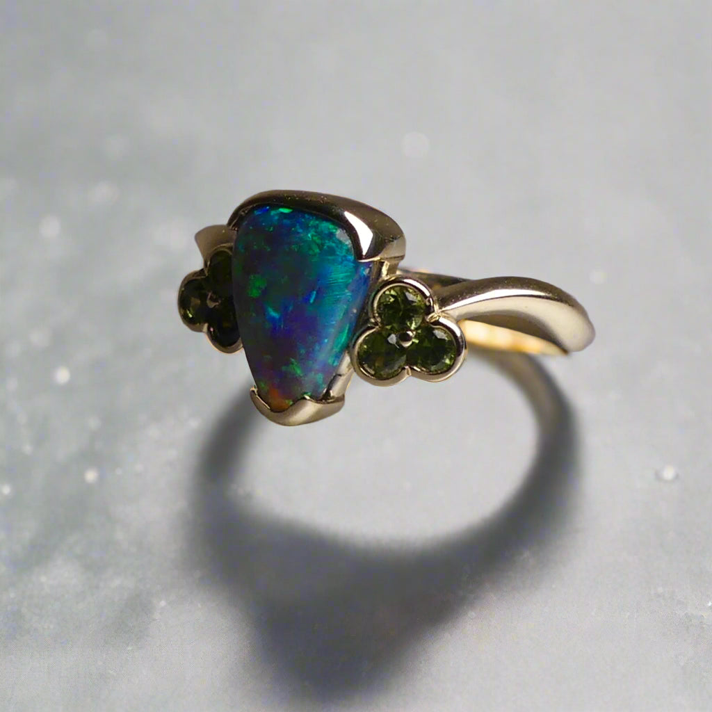 Indulge in timeless elegance with our 14k Australian Black Opal Ring. Crafted with a stunning black opal, this ring showcases mesmerizing blue and green colors. Each piece is unique, making it the perfect addition to any jewelry collection. Elevate your style with this timeless and luxurious ring.

Opal- 1.6ct Australian Black Opal

Origin-Lightning Ridge Australia

Setting- 14k Yellow Gold Bezel Set

Accent Stones- Forrest Green Sapphires

Size- 7 1/4 us
